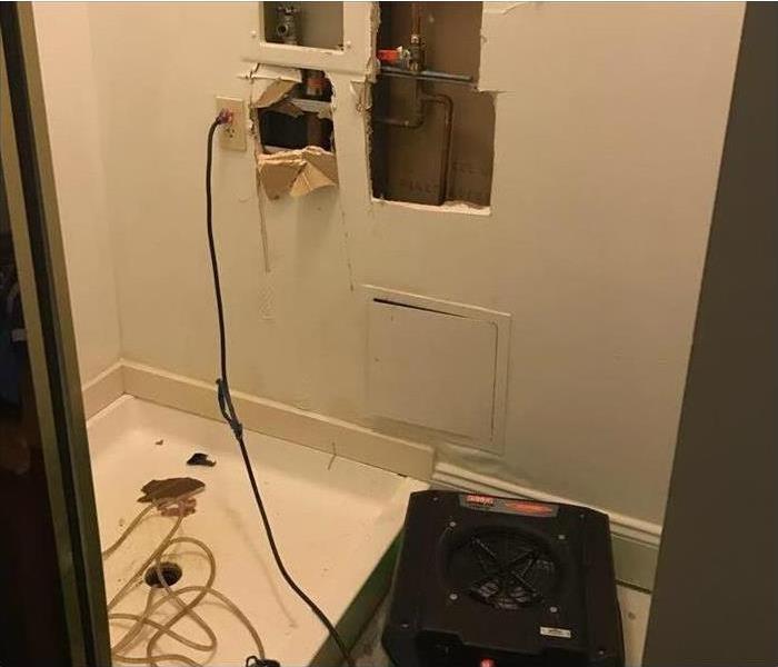 laundry room water damage with cut out holes to have pipe access