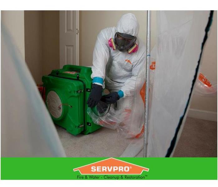 Gentleman in a biohazard suit attaching a plastic sleeve onto an air cleaner