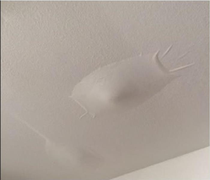 white ceiling with a water bubble on it being held by paint