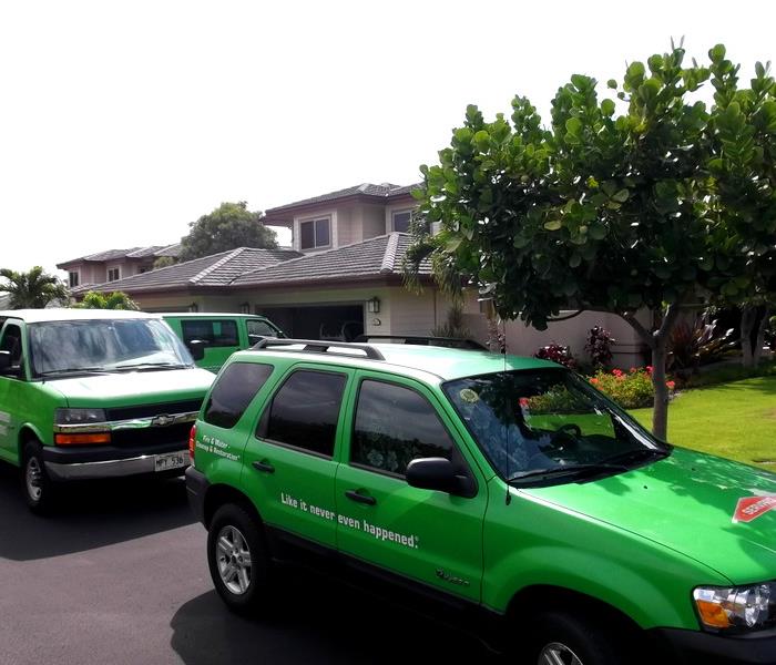 3 green painted SERVPRO vehicles parked outside a home